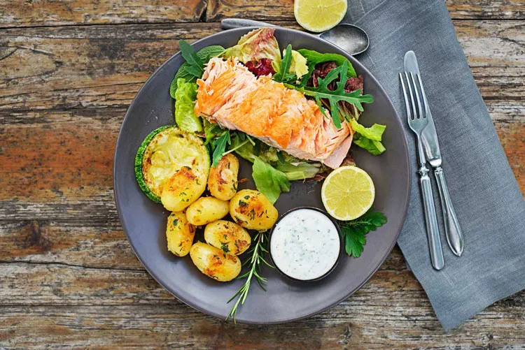 Schön angerichteter Teller mit einem gegarten Lachs Filet mit Ofen-Kartoffeln an Salatbouquet als Vitiligo-Sommerrezept mit antientzündlichem Potential und Quelle für Omega-3-Fettsäuren.